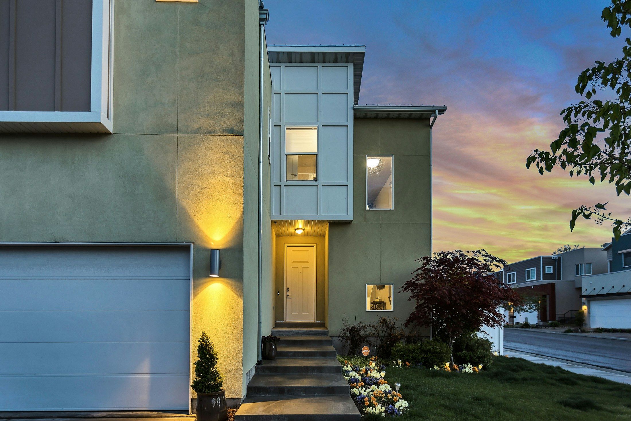 A two-storey house with its lights on at dusk