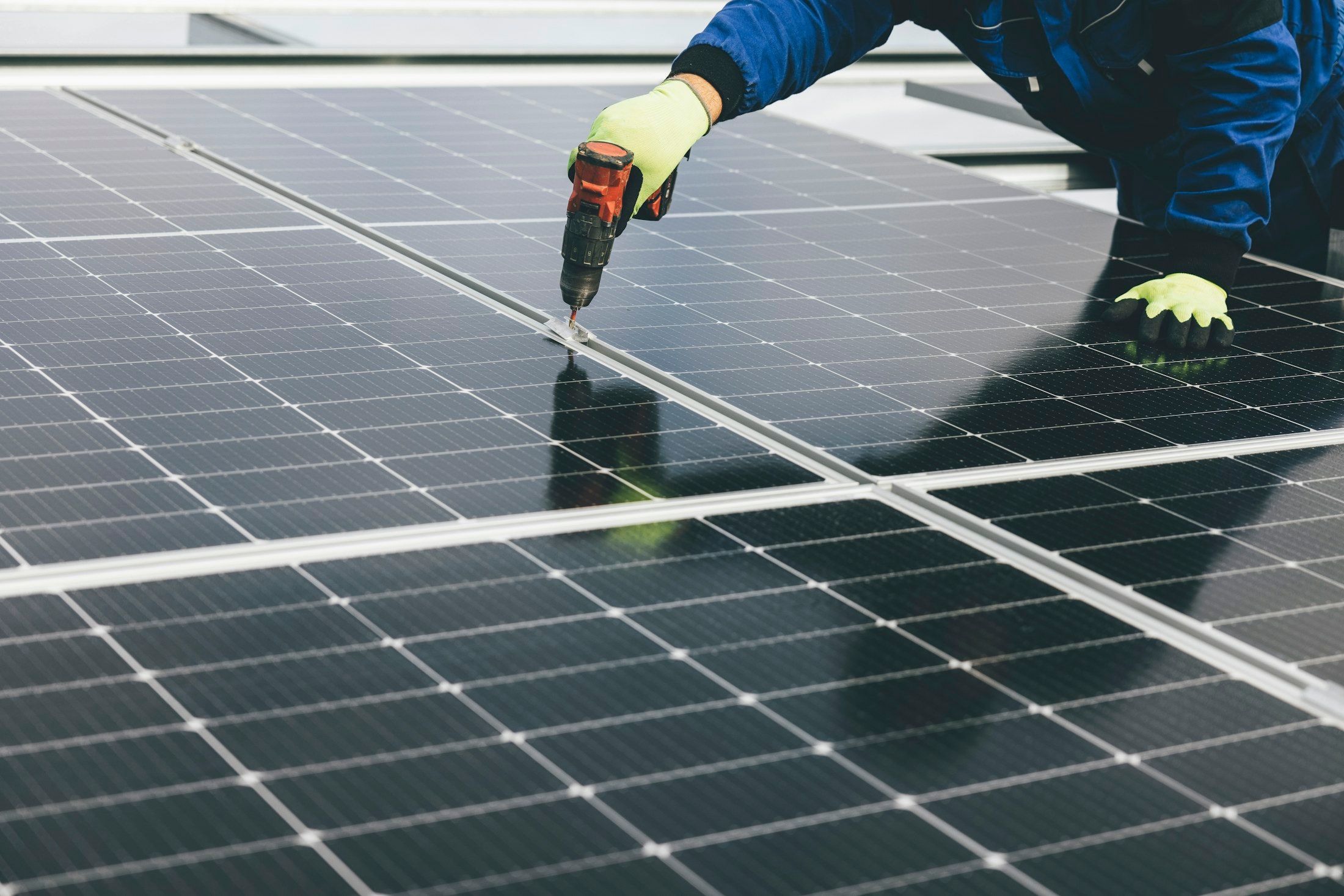 Gloved hands fasten a solar panel to its mounting rail