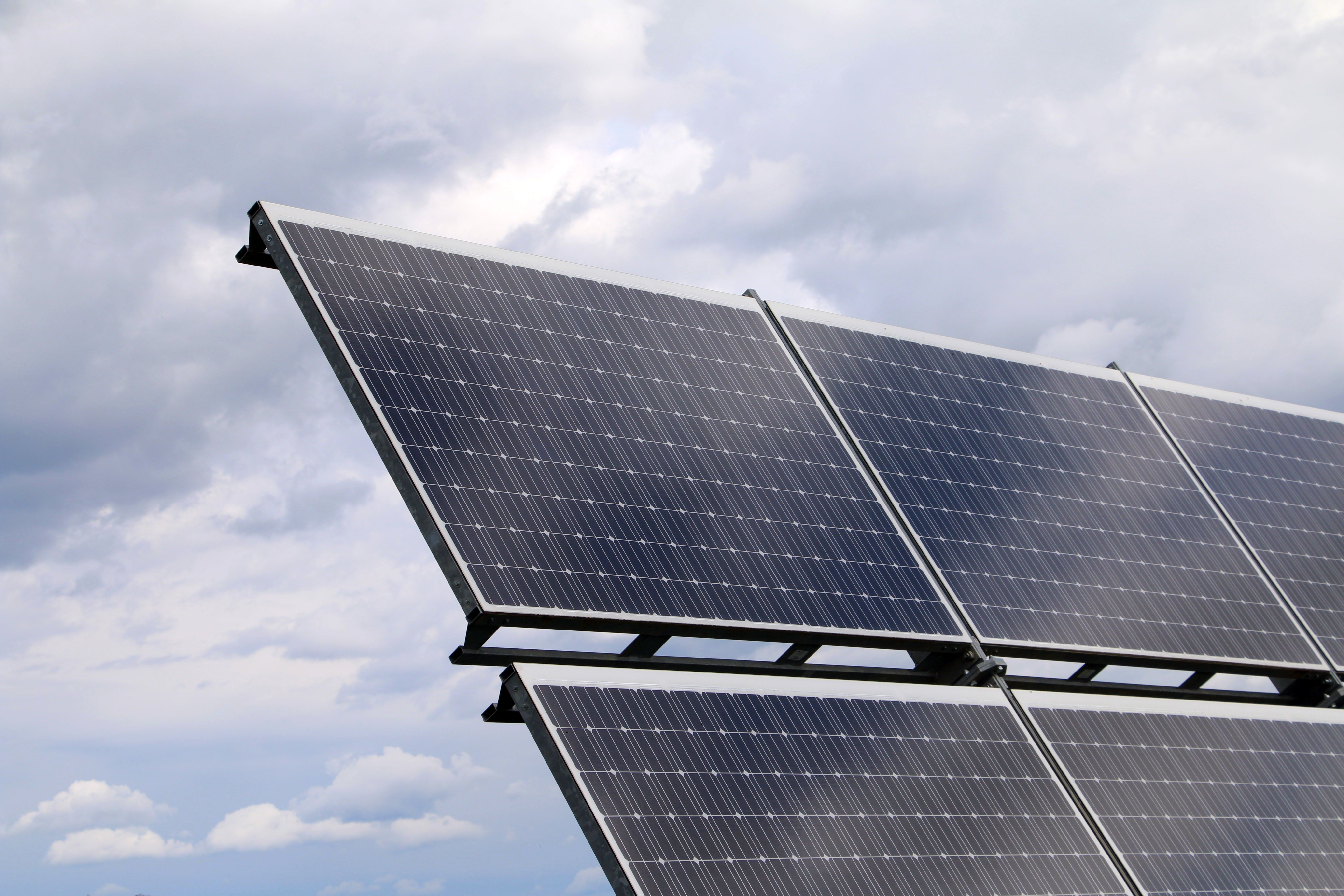 Close-up of several solar panels on a metal frame beneath a partly cloudy sky